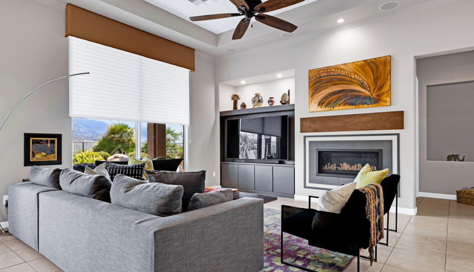 gray TV cabinet update with linear fireplace gray tile surround and walnut mantel. Copper wall art above and large windows on the left. Contemporary furniture.